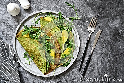 Pancakes with spinach, salmon and cheese on the kitchen table. View from above Stock Photo