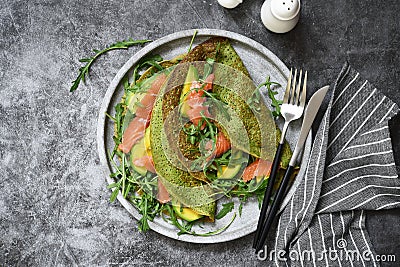 Pancakes with spinach, salmon and cheese on the kitchen table. View from above Stock Photo