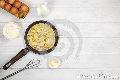 Pancakes, thin pancakes in a cast iron pan, on a white wooden background, copy space, top view. Stock Photo