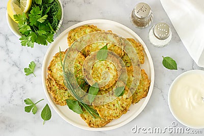 Pancakes from zucchini, served with sour cream or yogurt and various herbs. Useful vegetarian food. Stock Photo