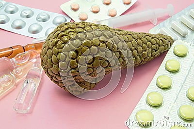 Pancreas treatment concept photo. Figure of pancreas surrounded by pills, medications, medicine vials with syringe, symbolizing tr Stock Photo