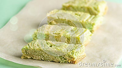 Pandan cake. Pieces of green cake with Pistachio nuts on paper. Korean dessert of Matcha tea. Vegan food Stock Photo