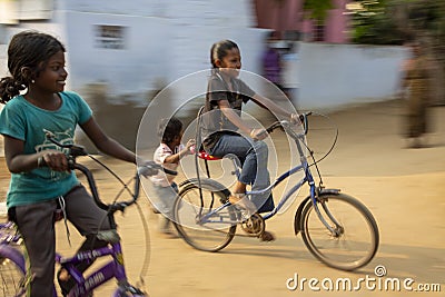 Panning shot of blurring and freezing effect of a girls chidren riding the bicycles. Editorial Stock Photo