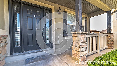 Pano frame Pillars and railing on the porch of a home with gray front door and sidelights Stock Photo