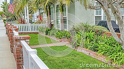 Pano Front yard of home with green lawn pathway wooden fence and red brick posts Editorial Stock Photo