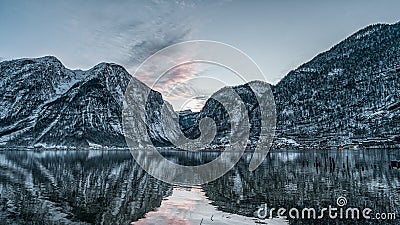 Pano view accross Hallstatt lake of the snowy village during sunset time in winter in Austria Stock Photo