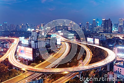 Panorama of Bangkok at dusk with skyscrapers in background and traffic trails on elevated expressways & circular interchanges Stock Photo