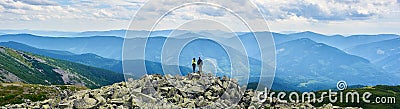 Panorama of Carpathian mountains with green forests, rear view pair is holding hands and enjoying powerful view. Stock Photo