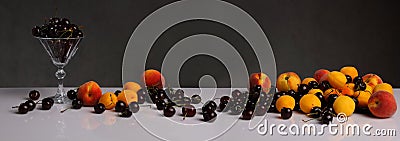 Panorama with cherries, peaches, apricots and a glass of wine on a dark background Stock Photo