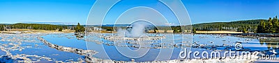 Panorama of circular tiered thermal pools reflecting the clear blue sky with a steaming center building pressure Stock Photo