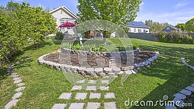 Panorama frame Landscaped grassy yard of home with lush trees and decorative concrete stones Stock Photo