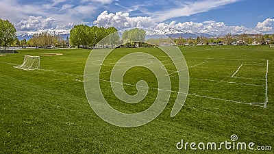 Panorama frame Vast sports field with soccer goal net and baseball bleachers behind a fence Stock Photo