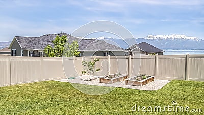 Panorama Grassy yard with view of rooftops lake and snow capped mountain under blue sky Stock Photo