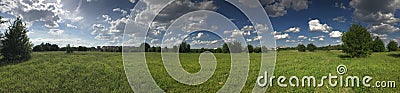 Panorama of a green meadow with bright green vegetation. Against the background of a bright blue sky with fluffy white clouds Stock Photo