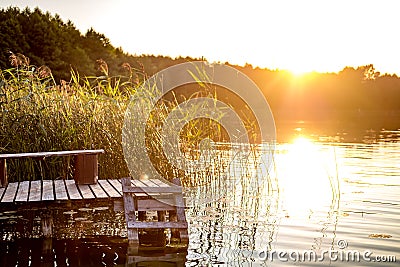 Panorama on huge lake or river near wooden pier in evening with beautiful awesome sunset Stock Photo