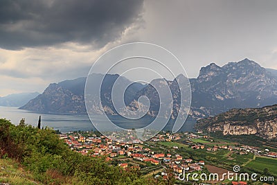 Panorama of Lake Garda, lakeside village Torbole and mountains with dark storm clouds, Italy Stock Photo