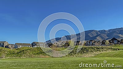 Panorama Narrow paved road on a vast grassy terrain covered with lush green grasses Stock Photo