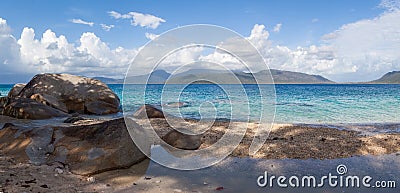 A panorama of a picturesque deserted blue lagoon with a sandy beach, a pleasant shade from a palm tree on a hot tropical day Stock Photo