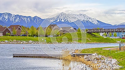 Panorama Picturesque lake scenery with wooden deck and rocks on the grassy shore Stock Photo