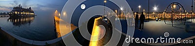 Panorama promenade in harbor cruise ship people relaxing in park blue fogy cloudy night sky with big moon street lantern blurred l Stock Photo