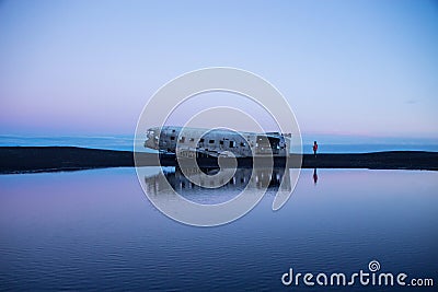 Panorama pond lake reflection of Solheimasandur DC3 airplane wreck crash site on black rock volcanic ashes beach Iceland Stock Photo