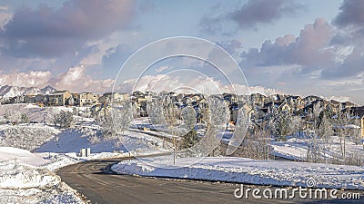 Panorama Puffy clouds at sunset Plowed road in the snow covered residential community of Draper Stock Photo