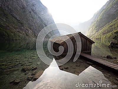 Panorama reflection of old wooden boat house shed alpine mountain lake Obersee Koenigssee Berchtesgaden Bavaria Germany Stock Photo