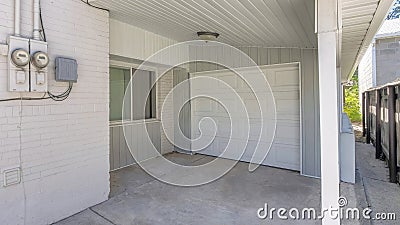 Panorama Small garage at the side of a house with white siding and two electricity meters Stock Photo