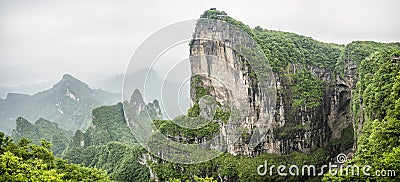 Panorama of the Tianmen Mountain Peak with a view of the cave Known as The Heaven`s Gate surrounded by the green forest and mist Stock Photo