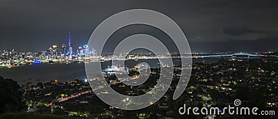 Panorama view of Auckland city at night, with Skytower on the left and Harbour bridge on the right of the image Editorial Stock Photo
