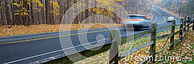 Panorama view busy traffic on curved winding country road cars traffic along wooden fence, colorful fall foliage leaves carpet Stock Photo