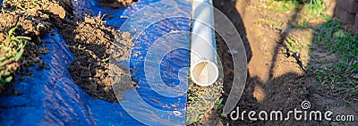 Panorama view plastic sewage pipes PVC, blue tarp with dirt, black mixing tub, pipe ready to laying, buried in ground trench, Stock Photo