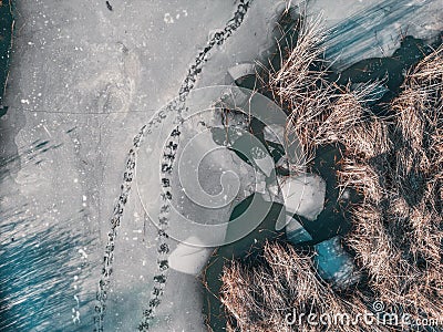Panoramic aerial view of a frozen lake with animal tracks and cracked ice. Animal tracks on the frozen surface of the lake Stock Photo