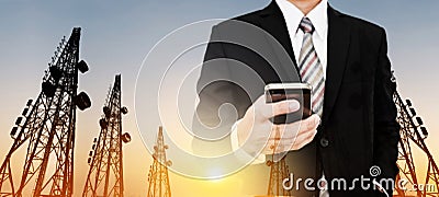 Panoramic, Businessman using mobile phone with Telecommunication towers with TV antennas and satellite dish in sunset Stock Photo