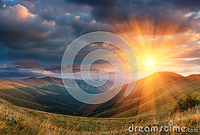 Panoramic landscape of fantastic sunset in the mountains. View of the autumn hills lit by the rays of the evening sun. Stock Photo