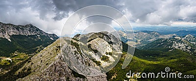 Panoramic landscape of mountain ridge and cloudy gray dramatic sky in the summer. Stock Photo