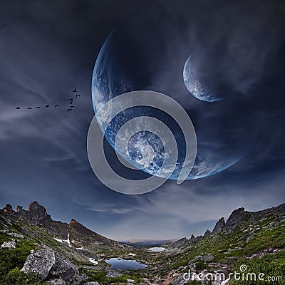 Panoramic mountains and two planets in sky. Fantastic world, birds flying against the background planets of moons. Sunset is Stock Photo