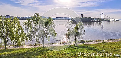 Panoramic reflection of riverbank trees, buildings and bridges Stock Photo