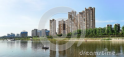 Panoramic reflection of riverbank trees, buildings and bridges Stock Photo