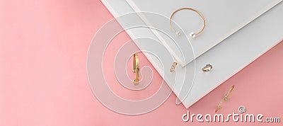 Panoramic shot of golden jewelries on pink and white paper background Stock Photo