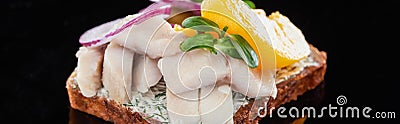 Panoramic shot of herring fish on delicious smorrebrod sandwich on black. Stock Photo