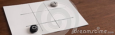 Panoramic shot of tic tac toe game on white paper with pebbles marked with naught and cross Stock Photo