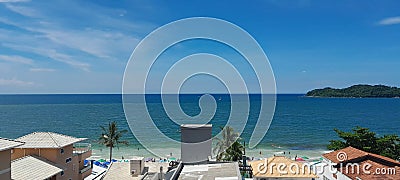 panoramic view of the blue sea and the horizon with silver and palm trees and roofs of houses with tiles and an island Stock Photo