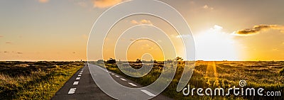 Panoramic View, on a dune landscape in the outback with a plain road to the horizon along the sunset in Denmark on the Island Romo Stock Photo