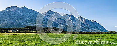 Panoramic view at five of Seven Sisters Mountain range on Sandnessjoen, ideally green grass, small Norwegian village and mountains Stock Photo