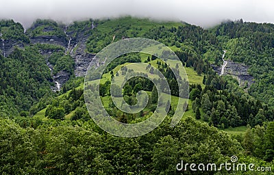 Panoramic view on mountain waterfalls, green forests and apline meadows near Saint-Gervais-les-Bains, Savoy. France Stock Photo