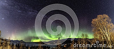 Panoramic view of multicolored spiky Aurora curved above Scandinavian mountains and frozen lake, very cold winter night, deep Stock Photo