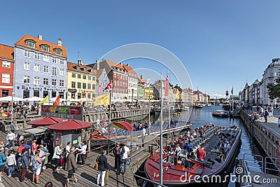Panoramic view at Nyhavn Canal in Copenhagen city. Colourful facades, old ships, touristic boats and crowd of tourists make Editorial Stock Photo