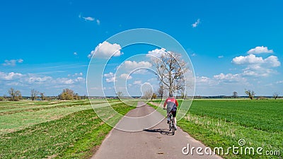 Panoramic view over countryside landscape and lonely cyclist cycling at cycling lane at sunny Spring day and blue sky. Concept Editorial Stock Photo