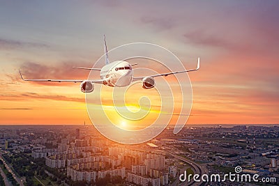 Panoramic view over the evening city during sunset, and a flying passenger plane Stock Photo